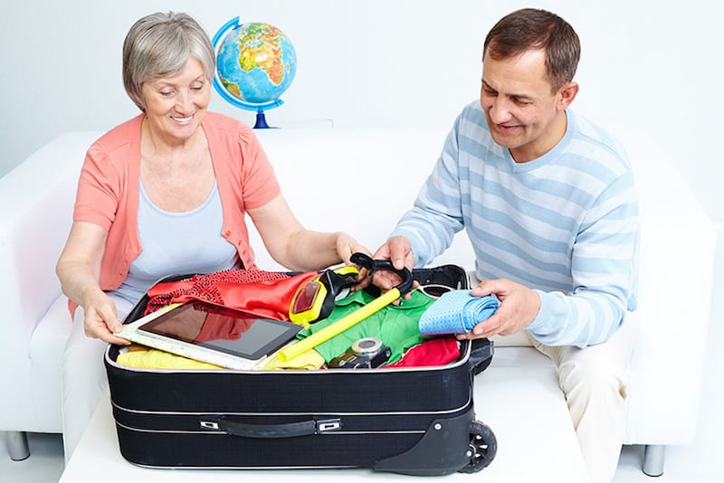 Una mujer mayor siendo ayudada por un hombre de mediana edad a preparar el equipaje