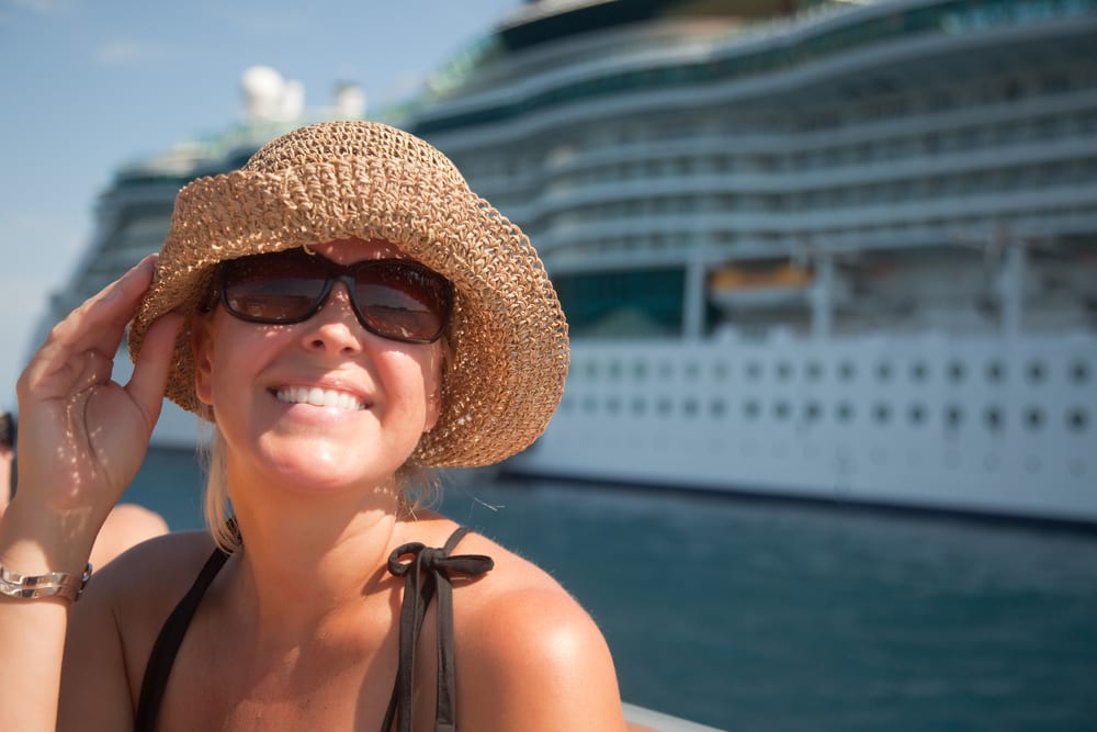 Mujer sonriendo delante de un crucero, en el puerto. Viaje curcero romántico