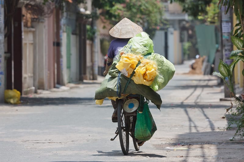 Mujer en bicicleta portando muchas cosas con ella. Viajar a Vietnam.